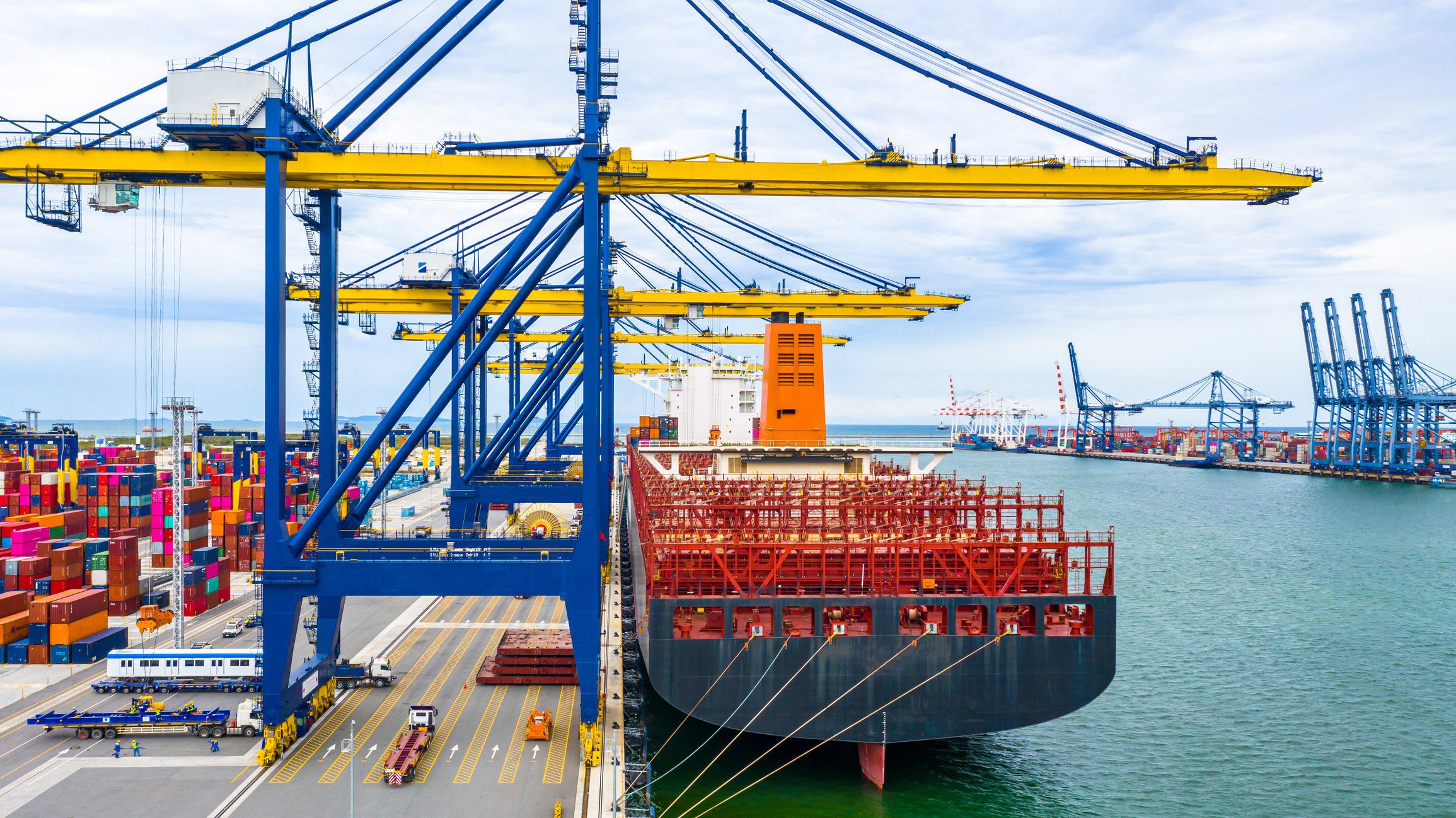 Aerial view cargo ship terminal, Unloading crane of cargo ship terminal, Aerial view industrial port with containers and container ship. Navigating Tariff Turbulence: Understanding the Impact on Transportation
